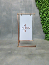 Load image into Gallery viewer, Copper Pipe Industrial Styled A Board Signage Frame Against Concrete Backdrop With Green Foliage To Side Of Rear Wall. Handmade By QuirkHub.