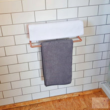 Load image into Gallery viewer, Copper Double Rail Towel Rail On White Brick Design Tiles With wooden floor and white towel and grey floor mat.